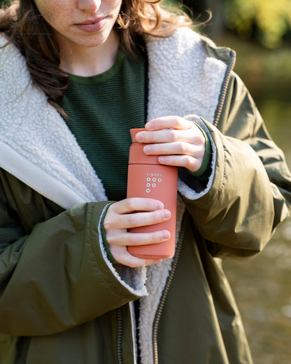 Women in the outdoors with her Ocean bottle and FINDRA Brew Flask in Sahara Red