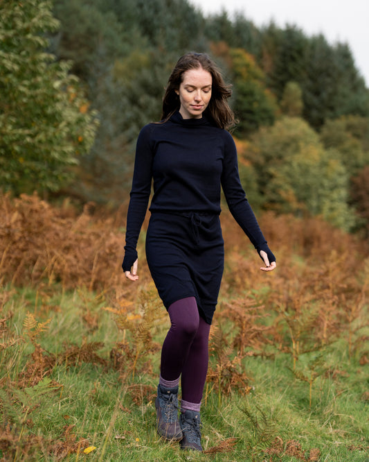 Woman in dark navy merino wool dress walking through a forest