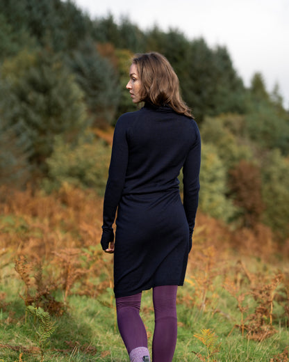Woman in a dark navy merino wool dress standing in a forest