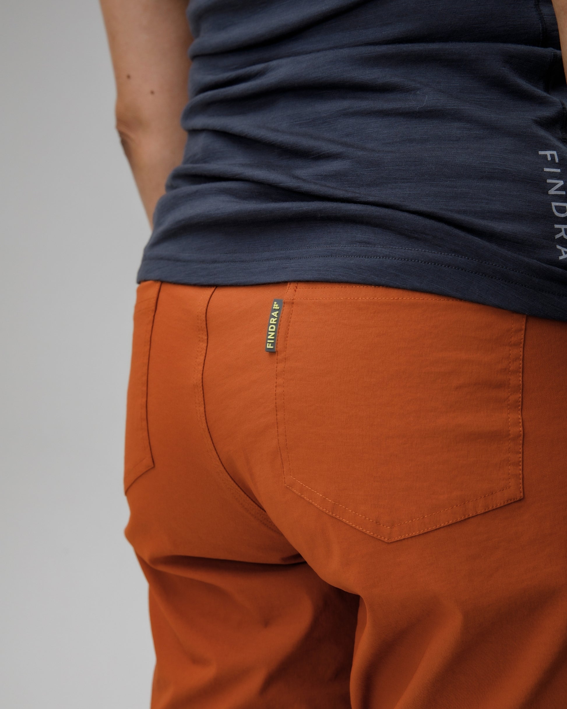 Person wearing orange pants with a visible brand logo on a gray background