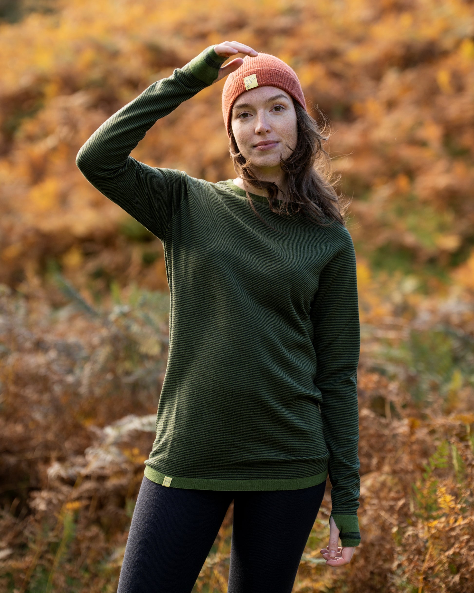 Woman with a FINDRA Base layer and a Chestnur red beanie in the autumn landscape