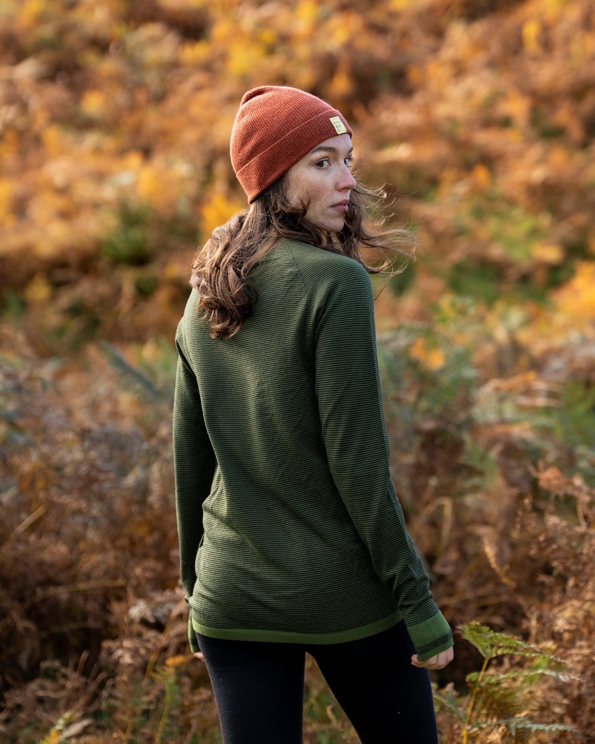Woman with a FINDRA Base layer and a Chestnut red beanie in the autumn landscape