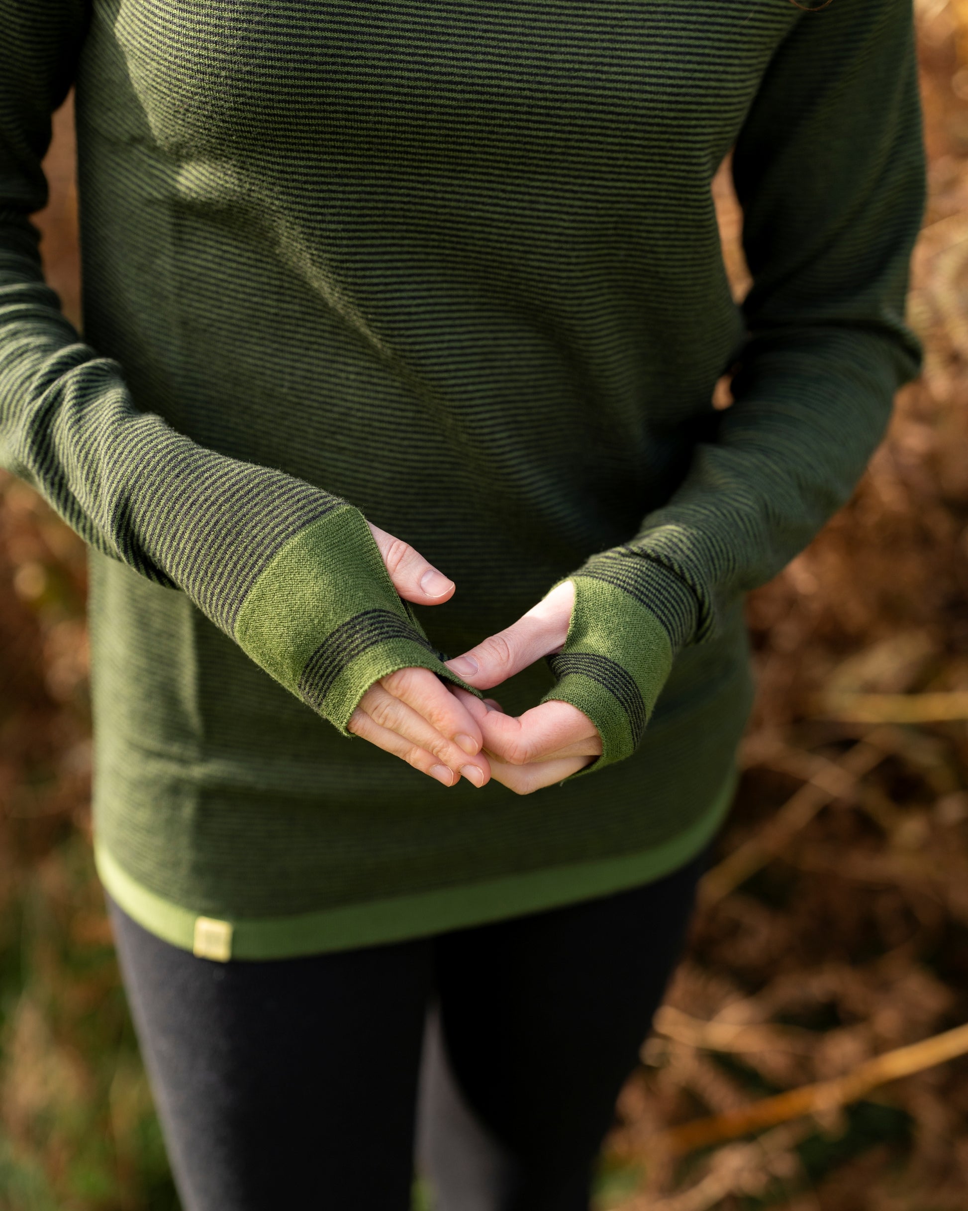 Person wearing green long-sleeve striped base layer with thumb passes on the sleeve in Green