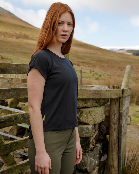 Woman standing in a field with mountains in the background