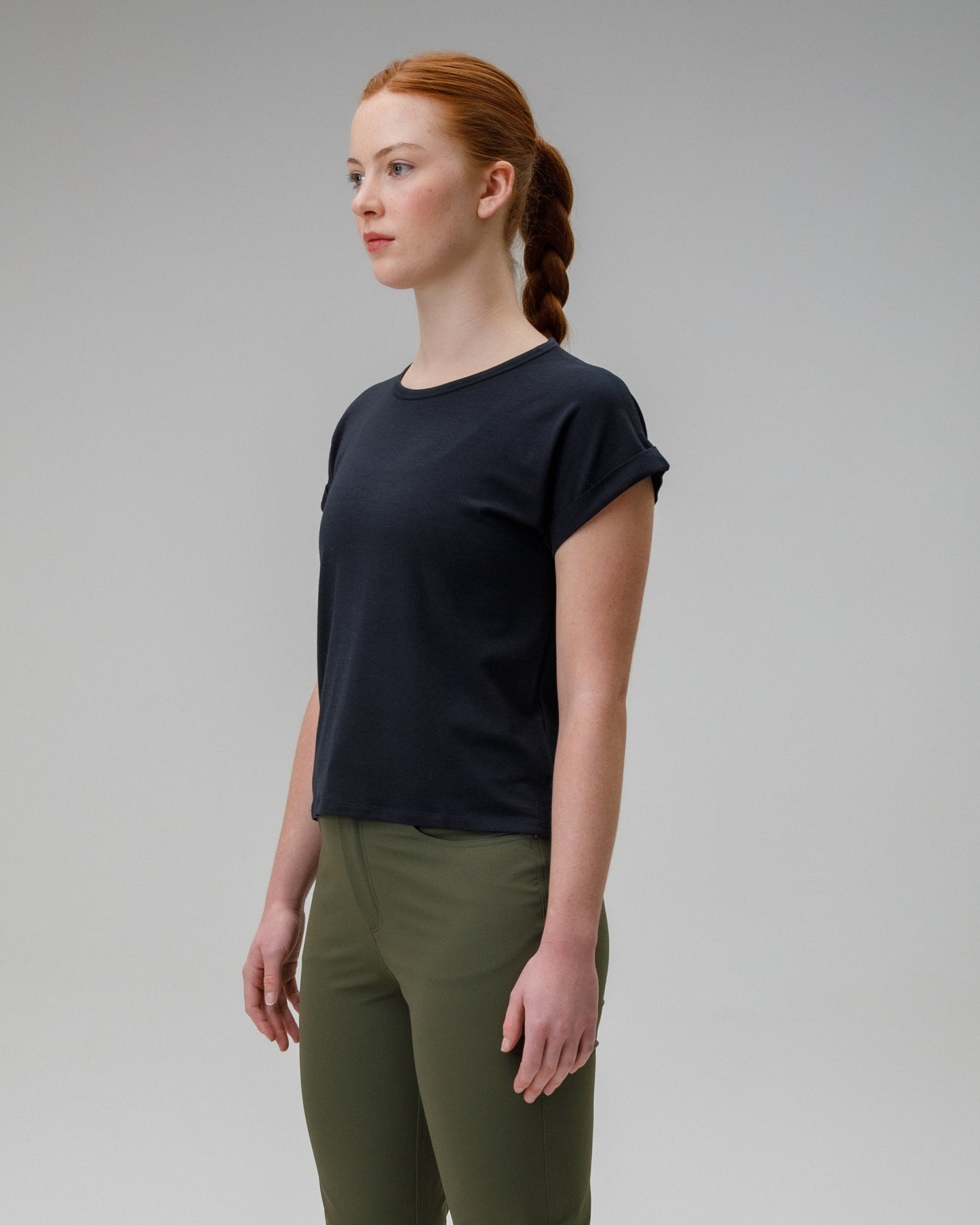 Woman wearing a black t-shirt and green pants against a gray background