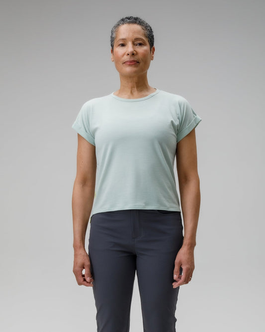 Person wearing a light green t-shirt and dark pants on a gray background