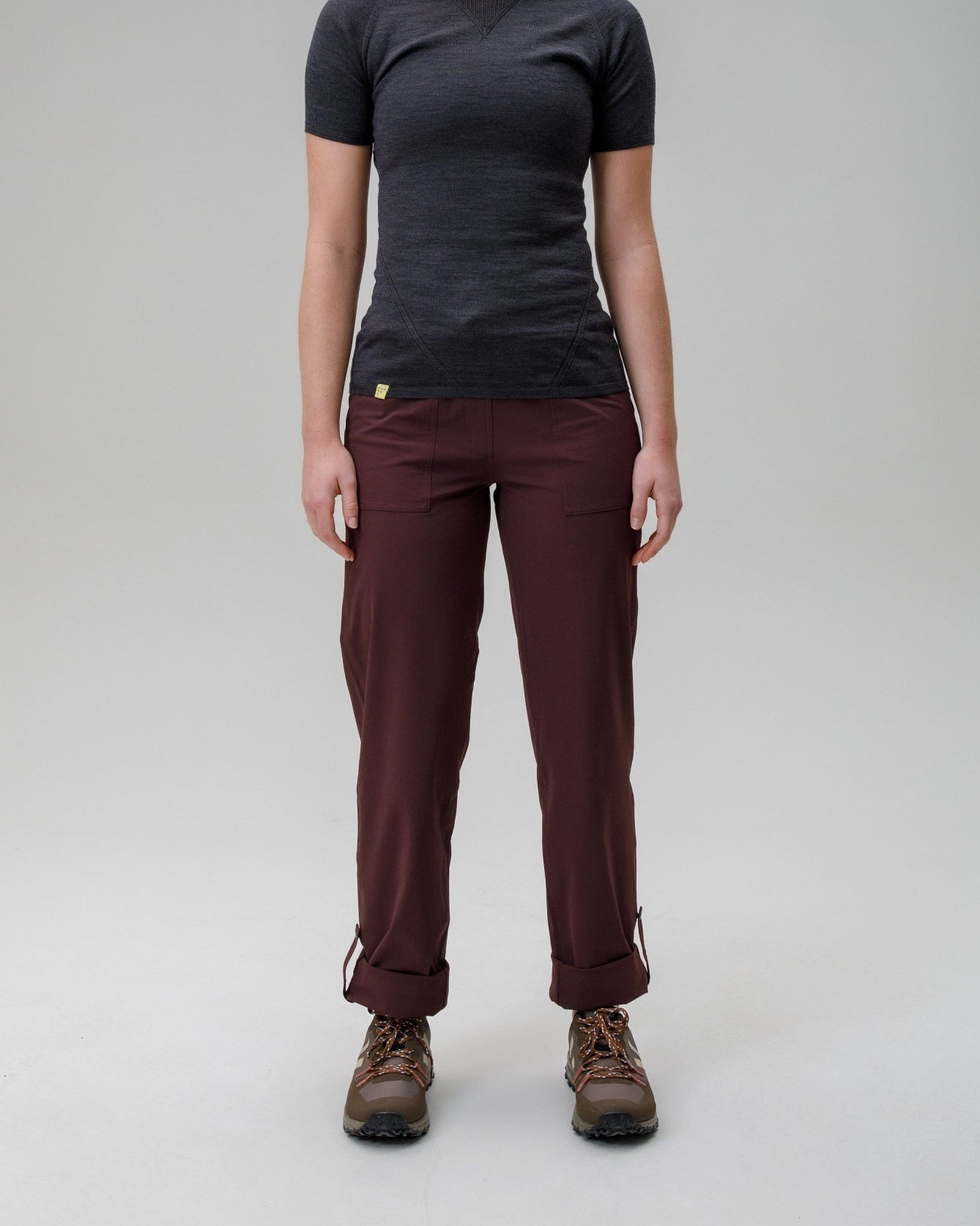 Person wearing a black t-shirt and maroon pants on a gray background