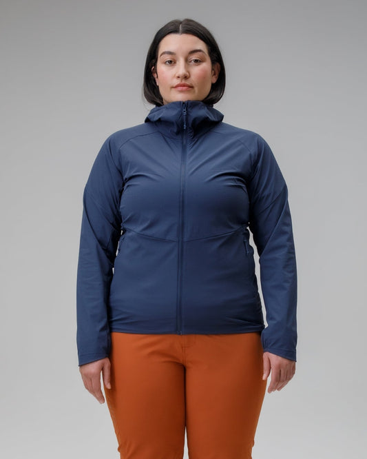 Woman wearing a blue jacket and orange pants on a gray background