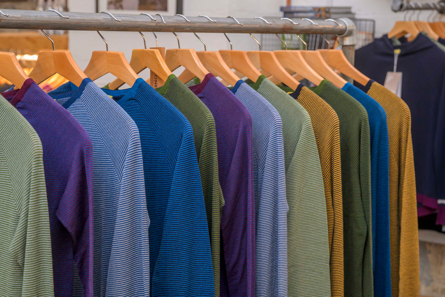 Row of colorful Merino Base Layers on hangers in a store
