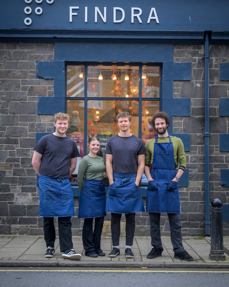 Four people wearing aprons standing in front of a building with 'FINDRA' branding.