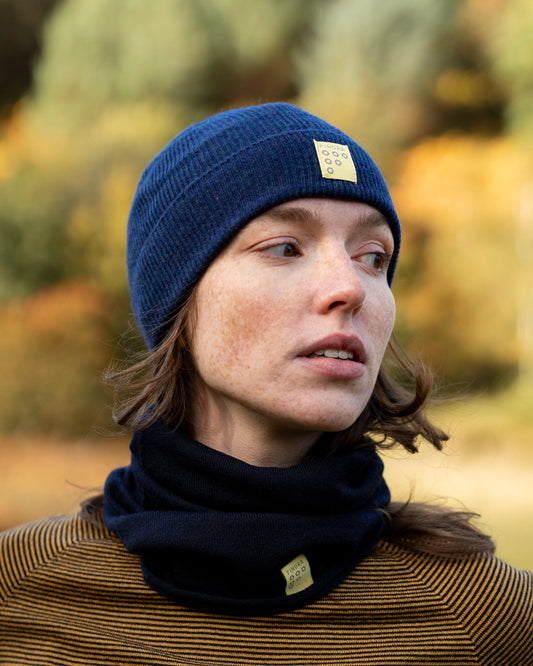 Person wearing a blue beanie and black scarf with a blurred natural background