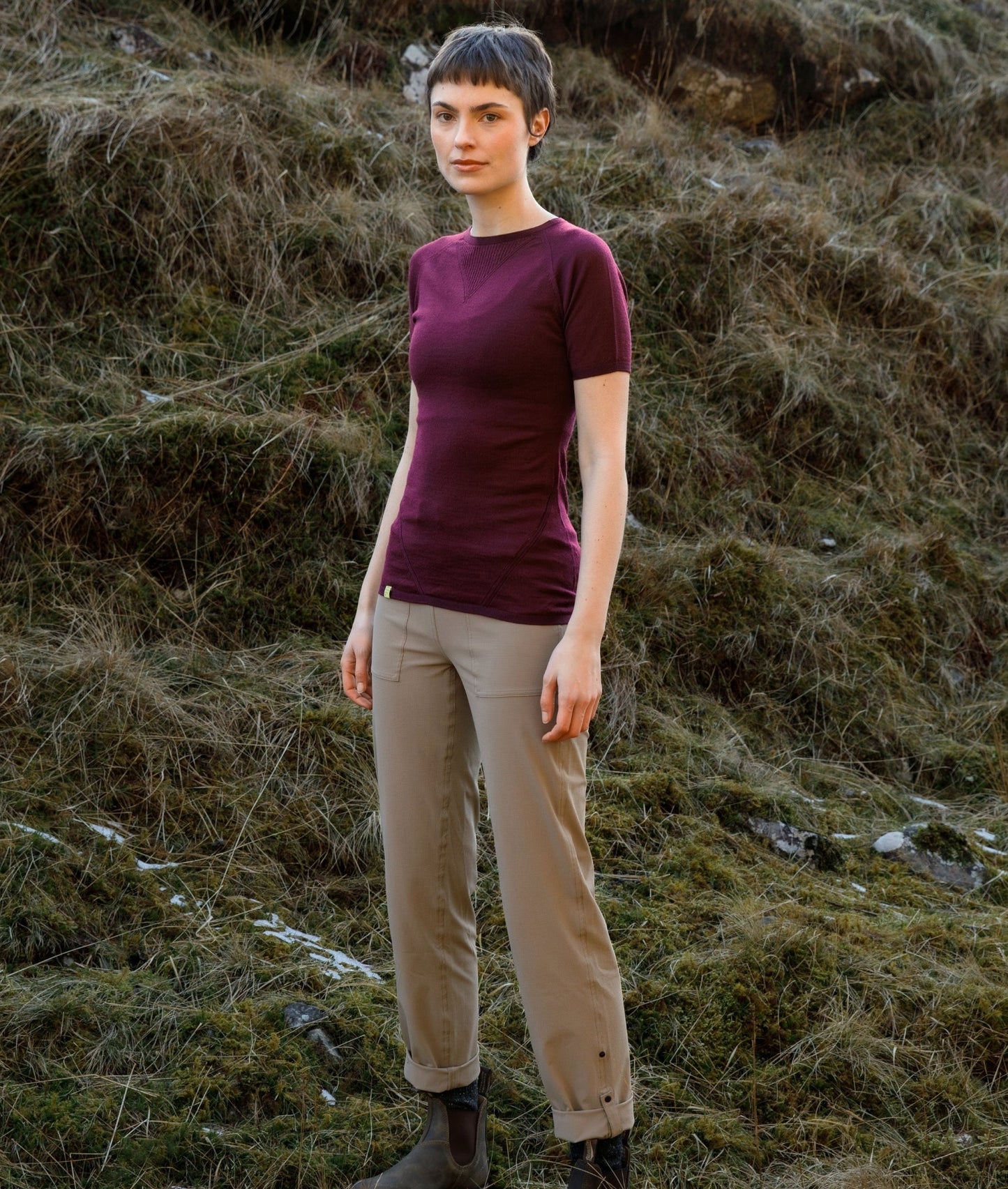 Person wearing a purple shirt and beige pants standing in a natural setting