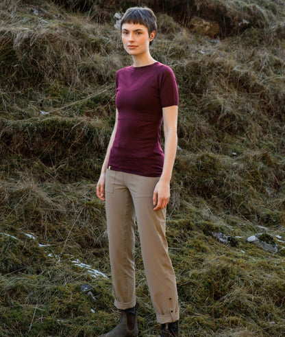 Person wearing a purple shirt and beige pants standing in a natural setting