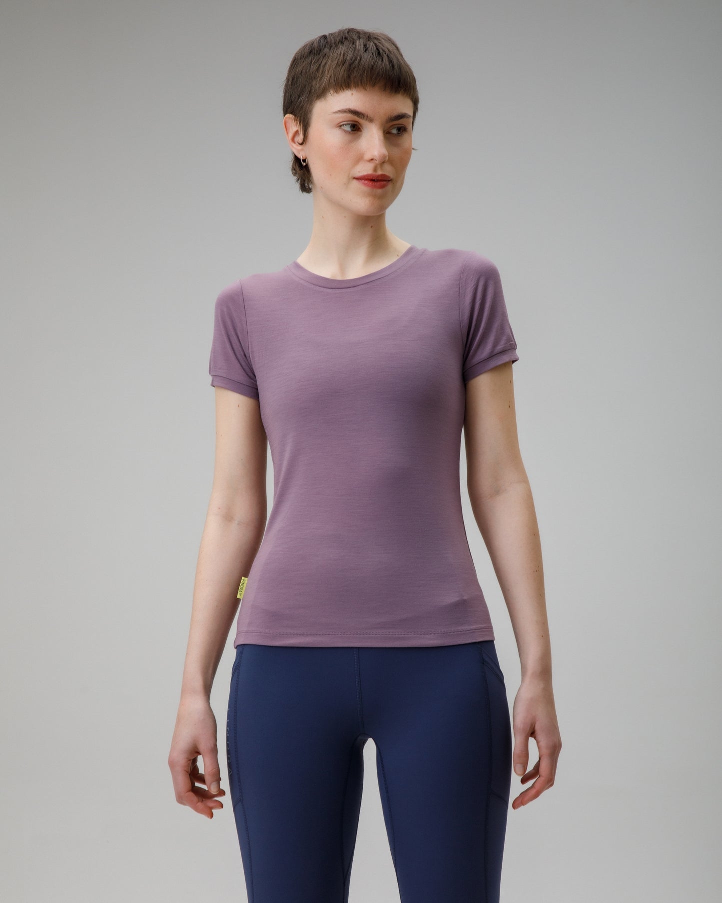 Woman wearing a purple t-shirt and blue leggings on a gray background