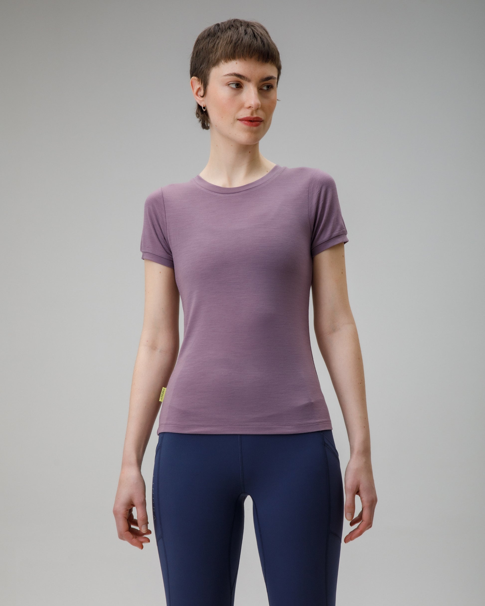 Woman wearing a purple t-shirt and blue leggings on a gray background