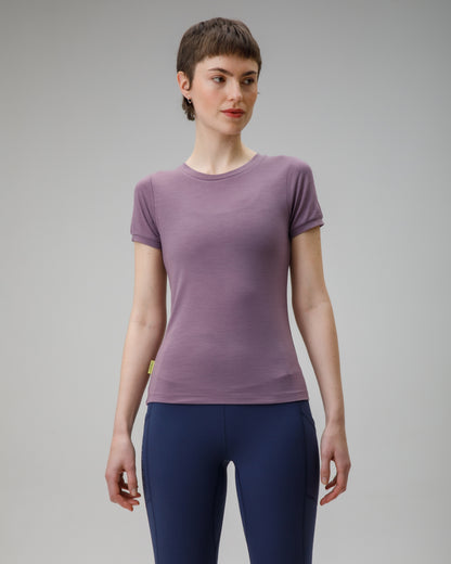 Woman wearing a purple t-shirt and blue leggings on a gray background
