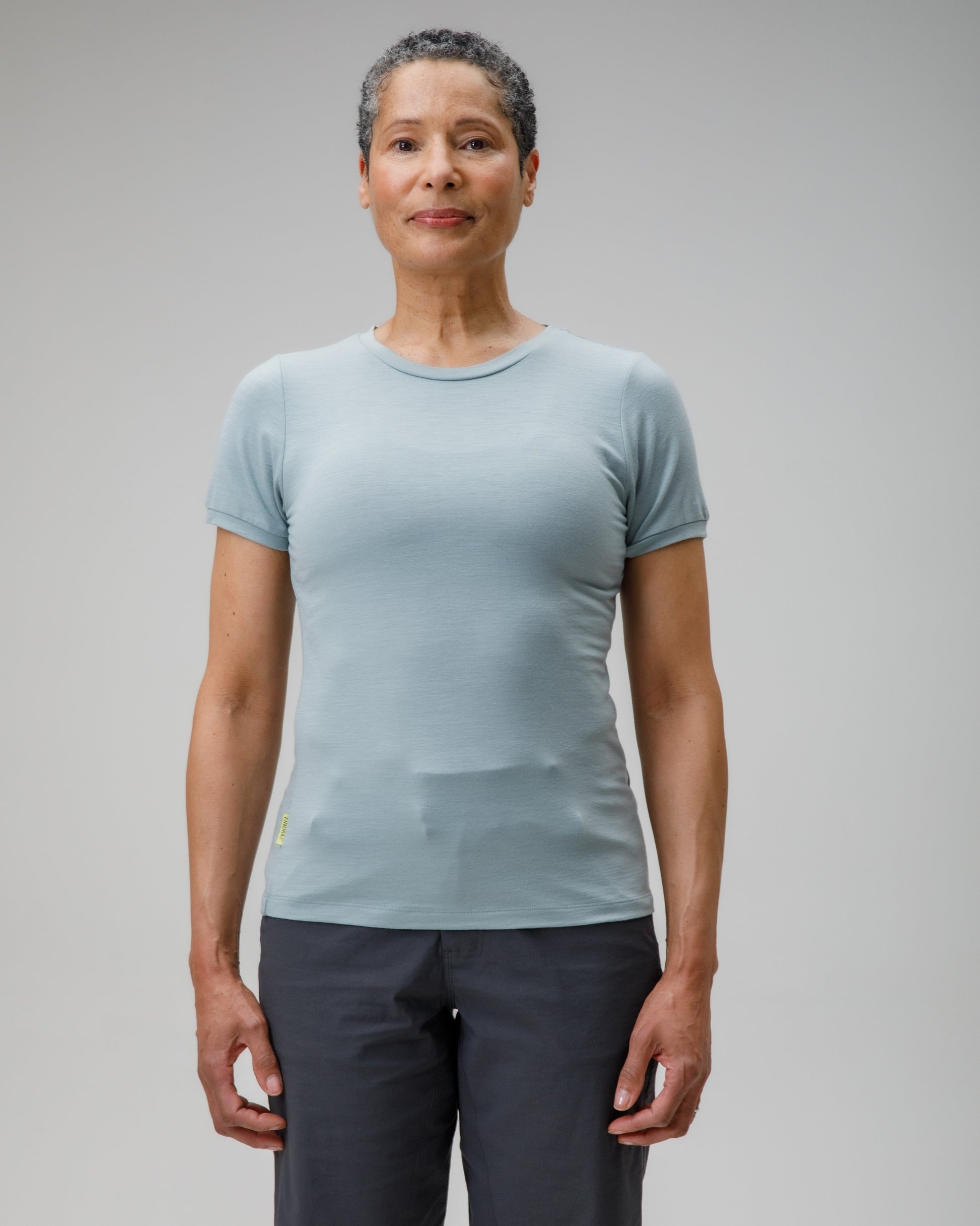 Person wearing a light blue t-shirt and dark pants on a gray background