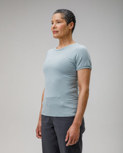 Person wearing a light blue t-shirt and dark pants on a plain background