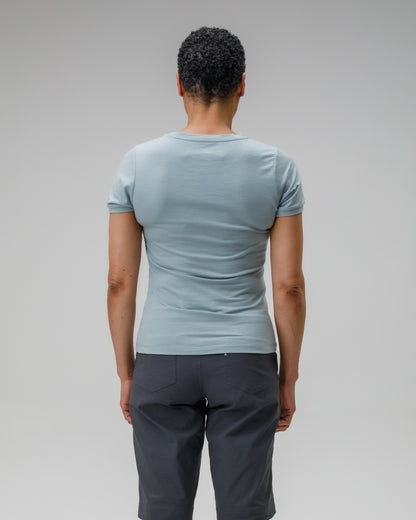 Person wearing a light blue t-shirt and dark gray pants on a plain background