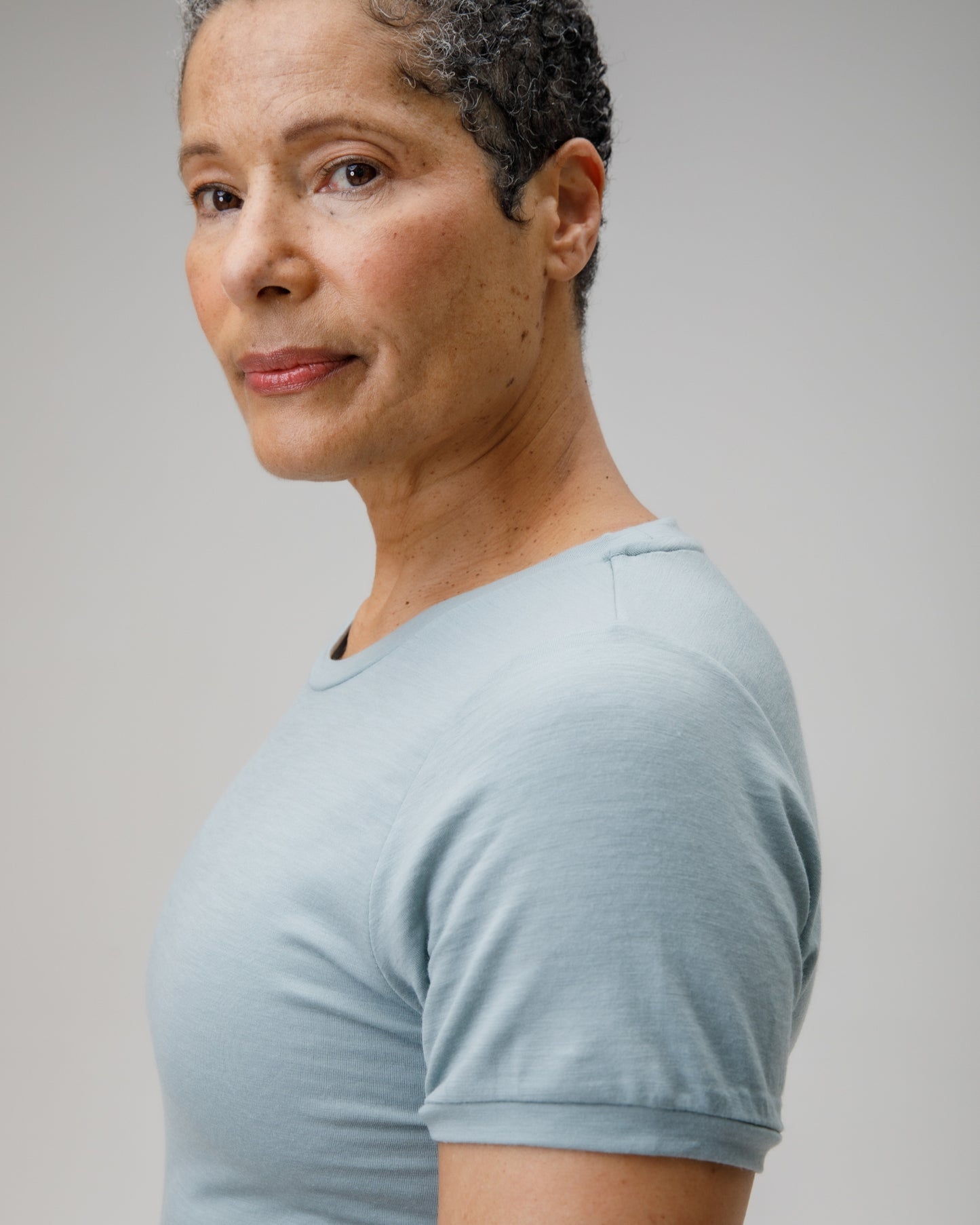 Woman wearing a light blue t-shirt against a plain background
