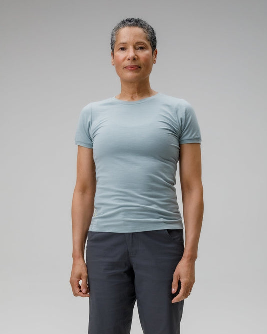 Person wearing a light blue t-shirt and dark shorts on a gray background