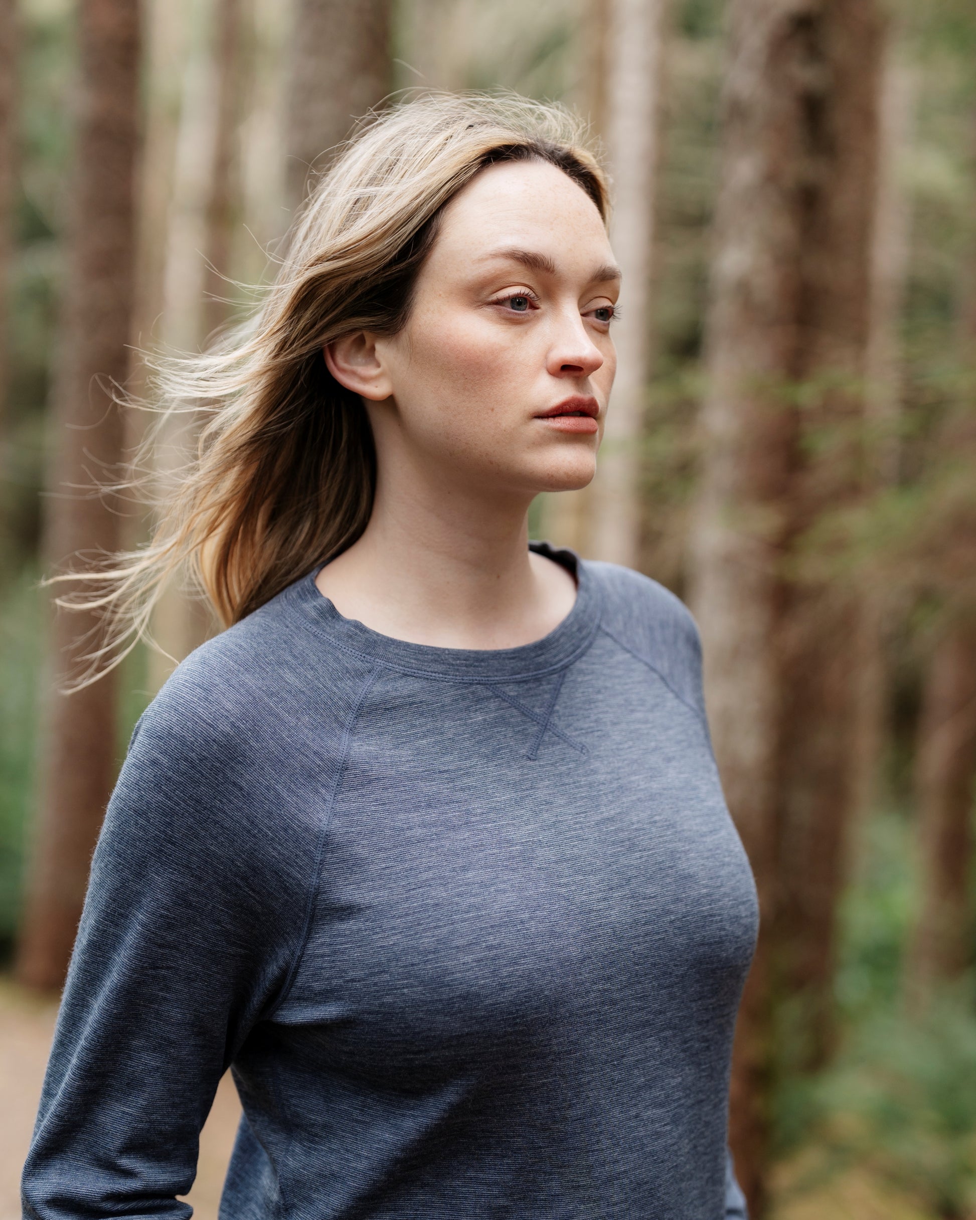 Woman wearing a blue sweater standing in a forest